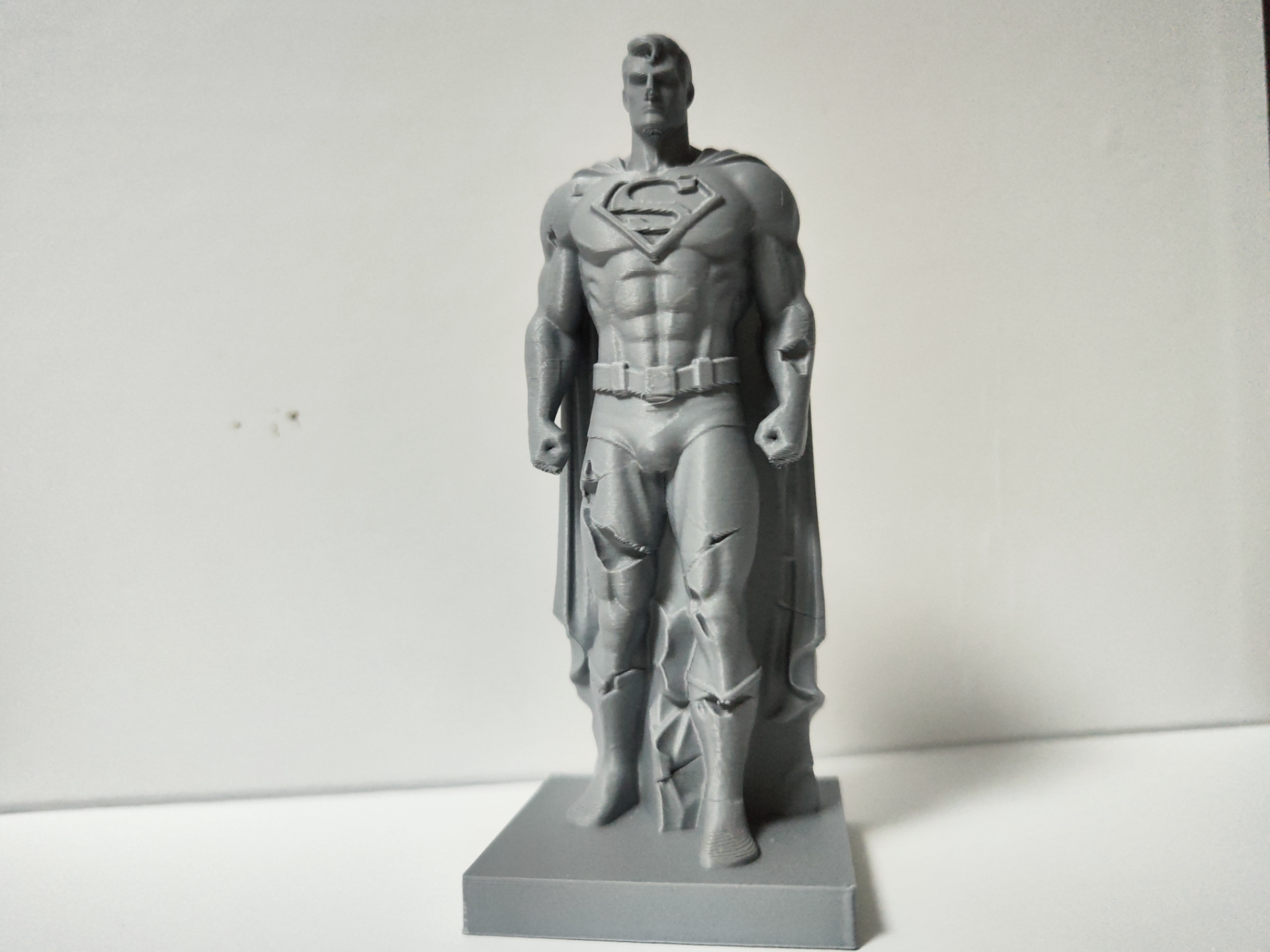 damaged standing stone sculpture of Superman