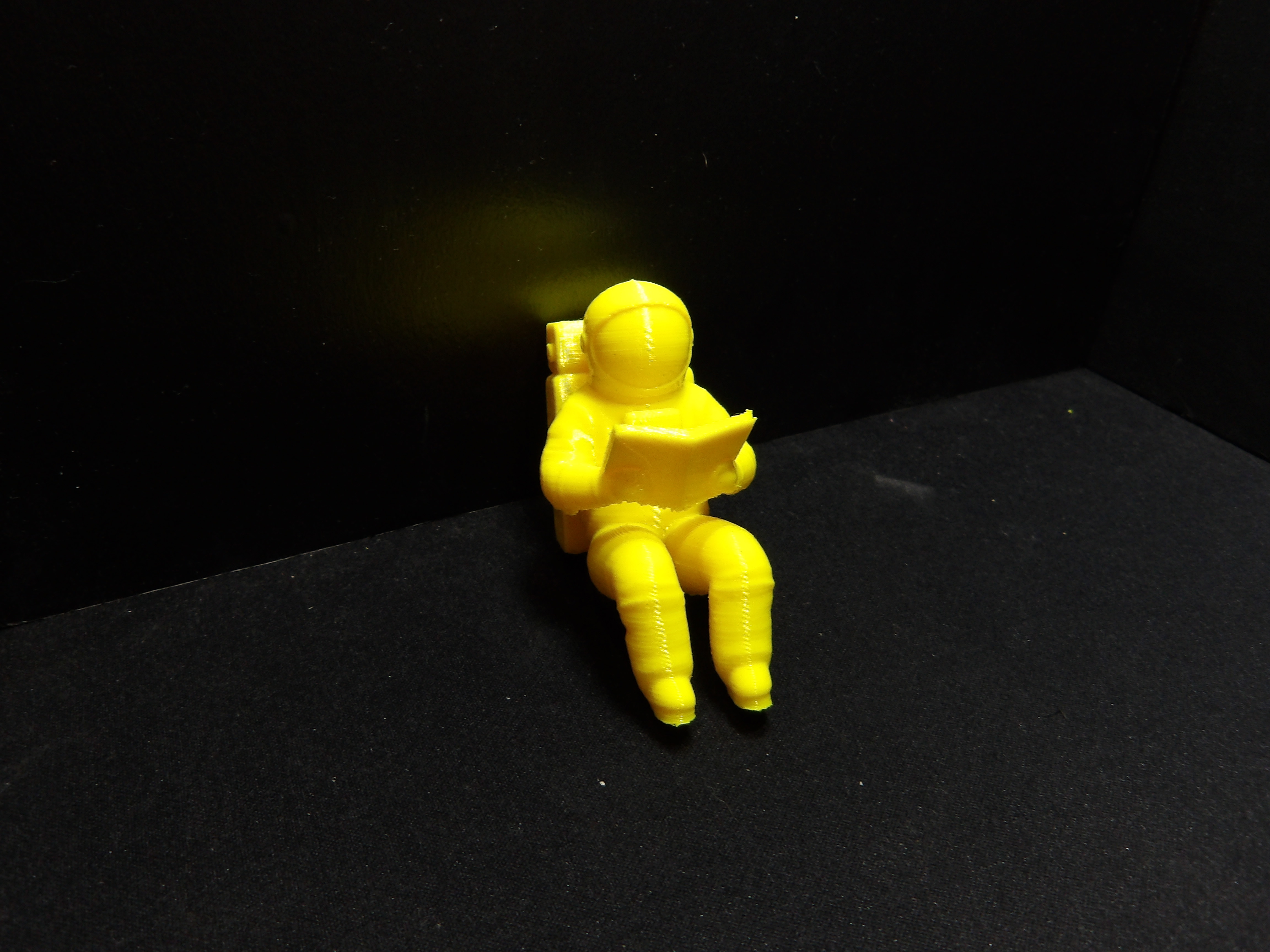 Astronaut reading a book with a closed visor.